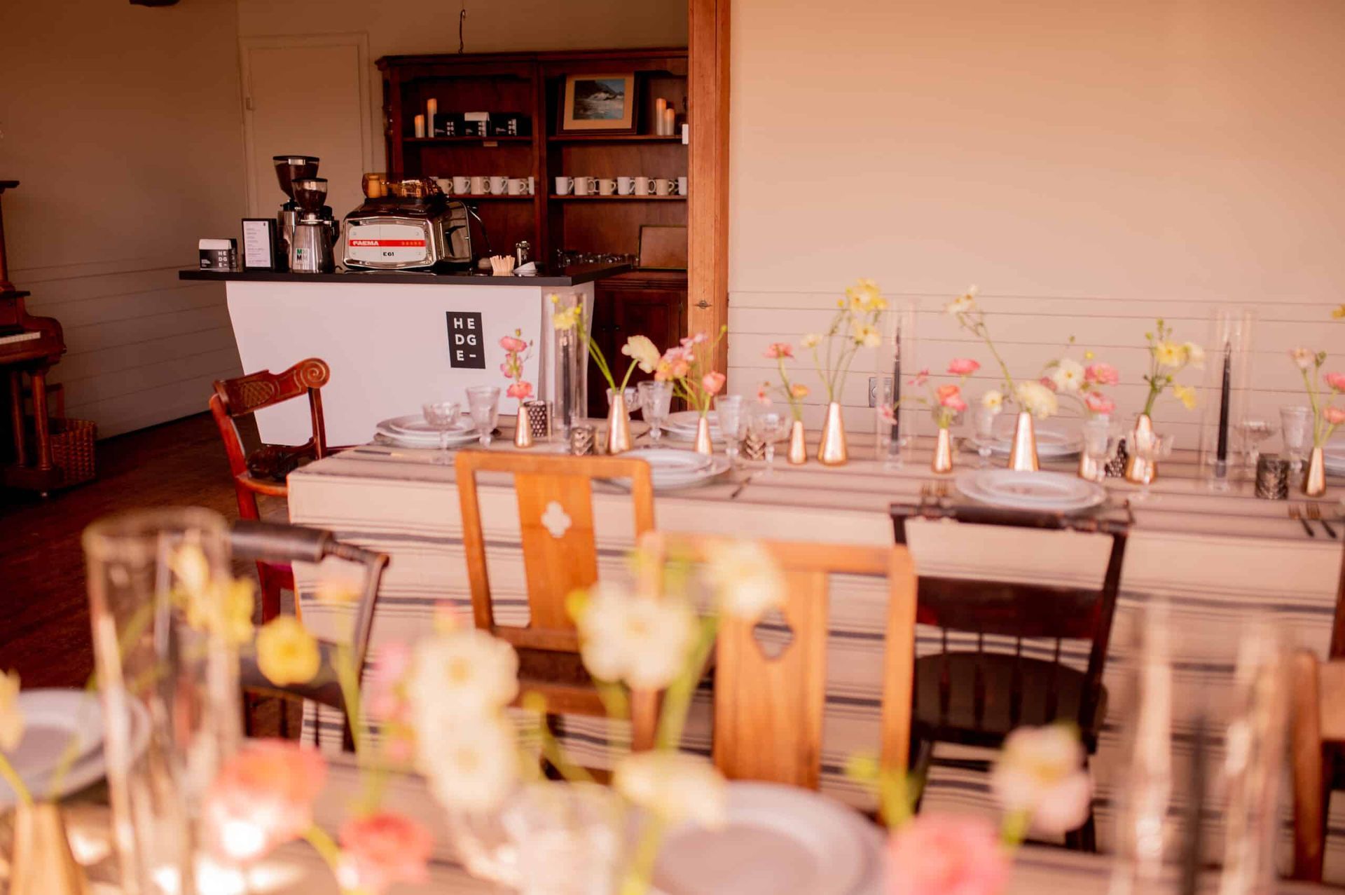 Wedding reception table setting with floral arrangements, tableware, and vintage chairs.