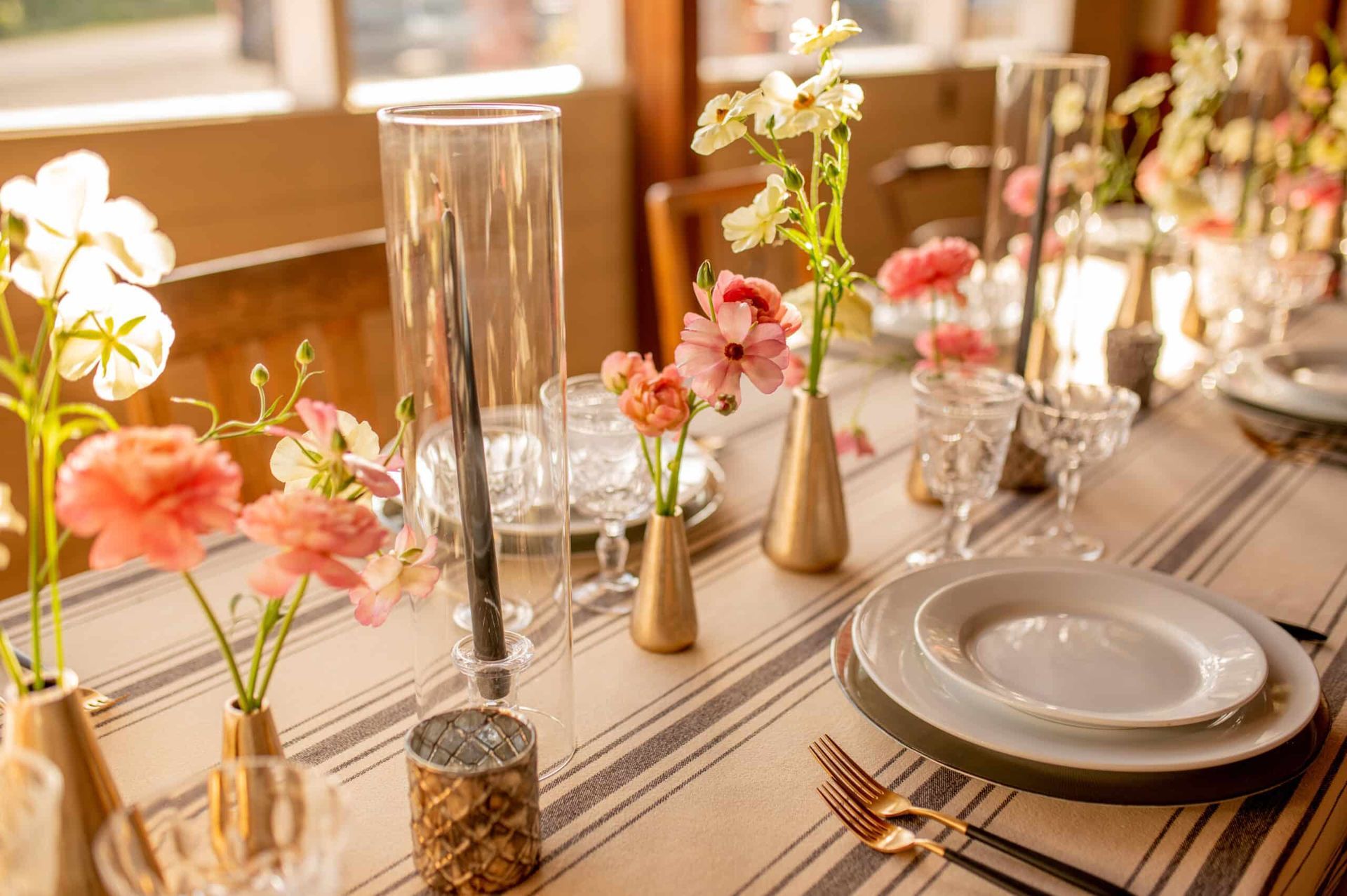 Table setting with floral centerpieces, candles, and place settings; soft colors.