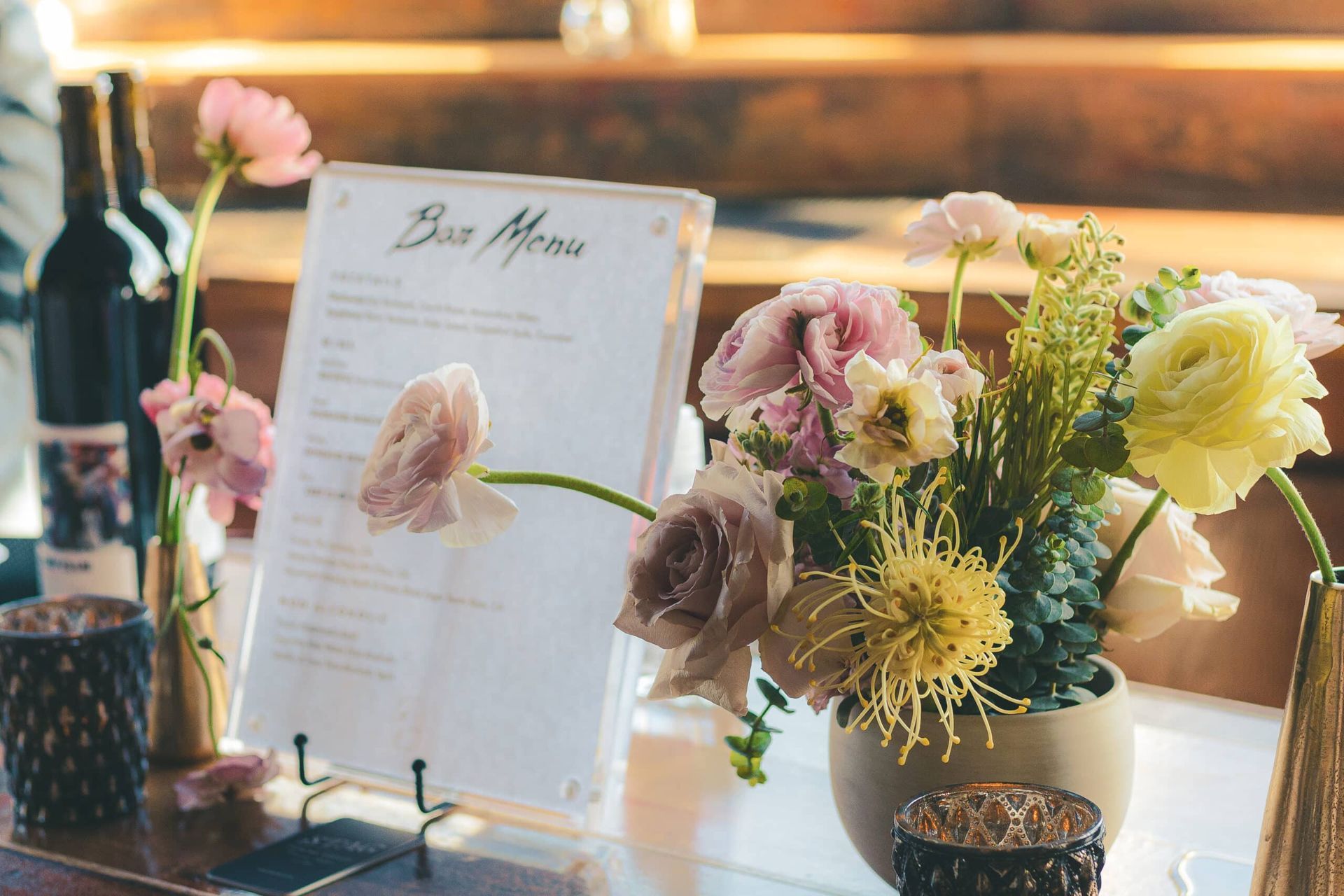 Bar menu with flowers and wine bottles on a table.