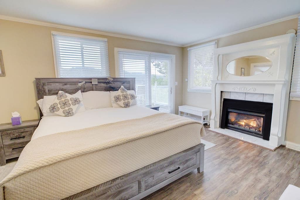 Bedroom with bed, fireplace, sliding door, and windows.