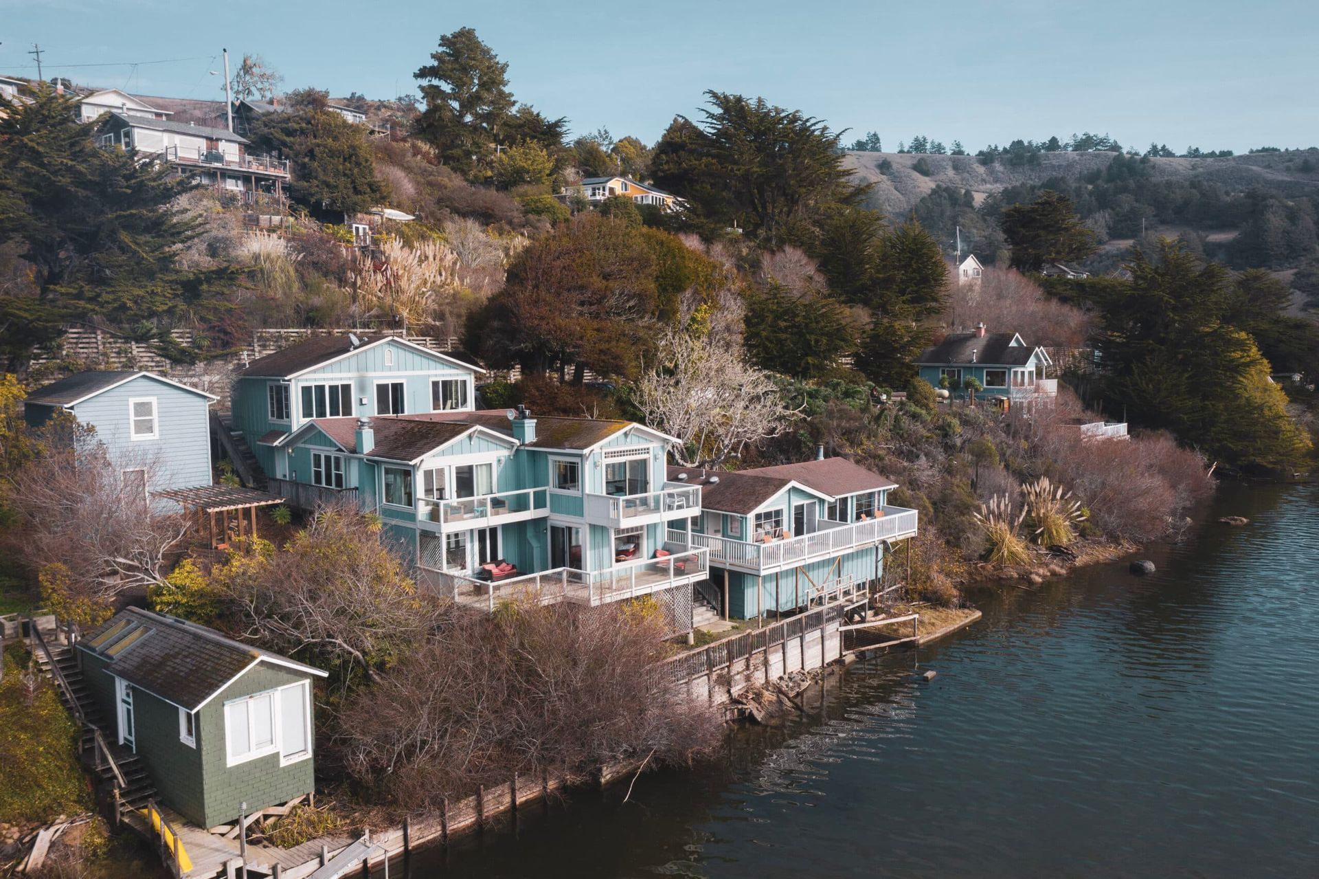 Houses with balconies on a hillside by a lake.
