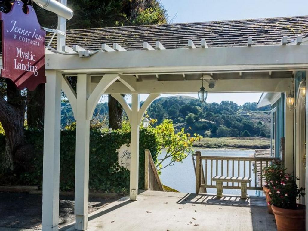 Covered walkway at a restaurant with sign, water view, and bench.