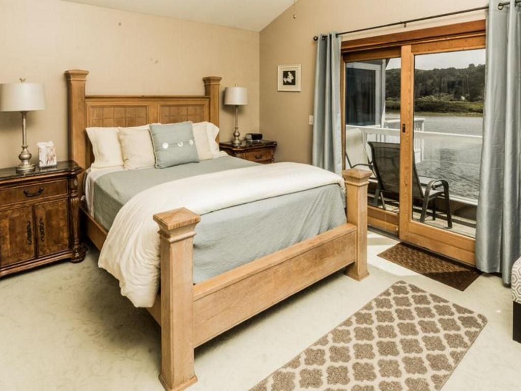 Bedroom with a light-colored wooden bed, nightstands, and a door leading to an outdoor deck.