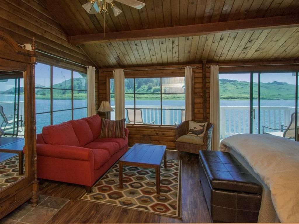 Cozy cabin interior with a red sofa, water views, and a bed.