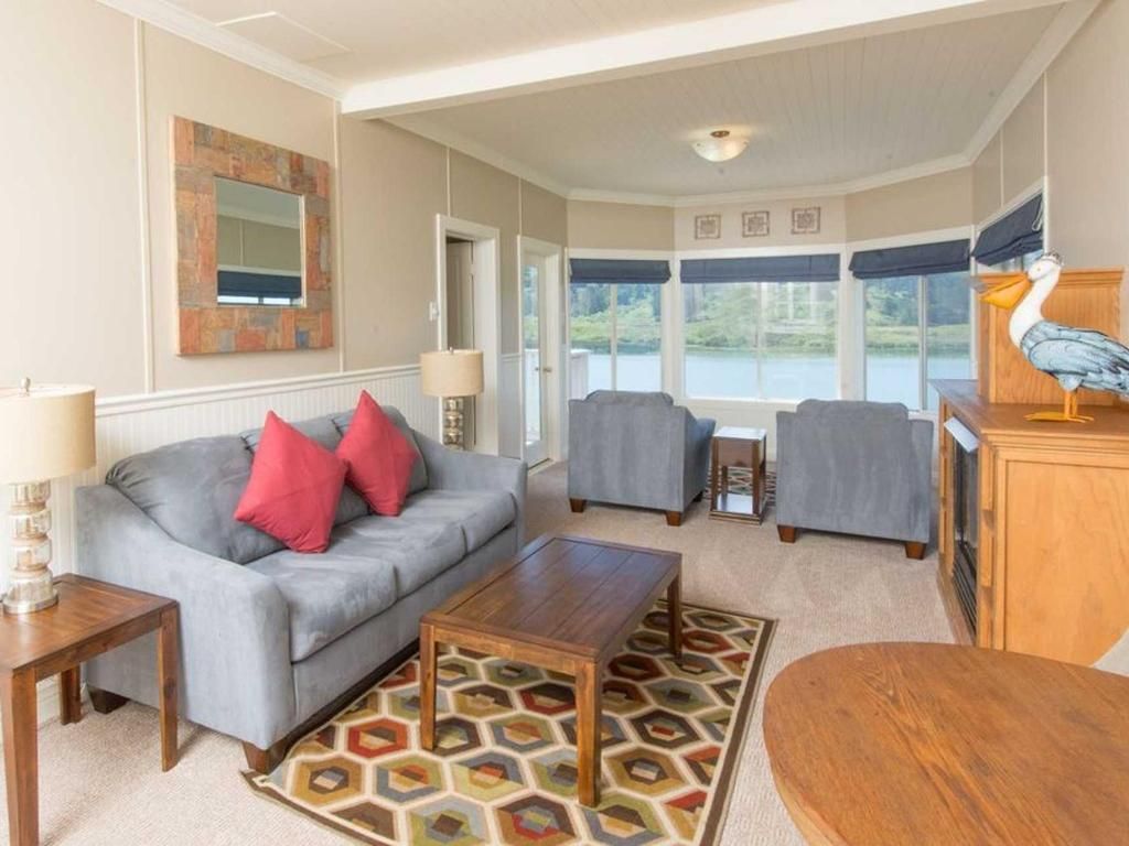 Living room with gray sofa, armchairs, coffee table, rug, and lake view windows.