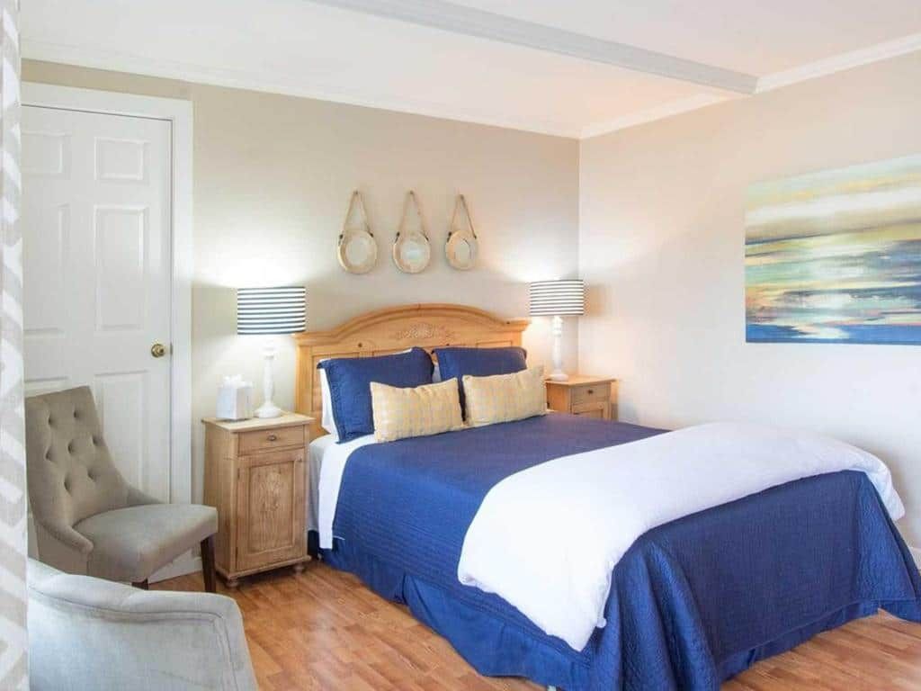 Bedroom with blue bedding, beige walls, wooden furniture, and coastal decor.