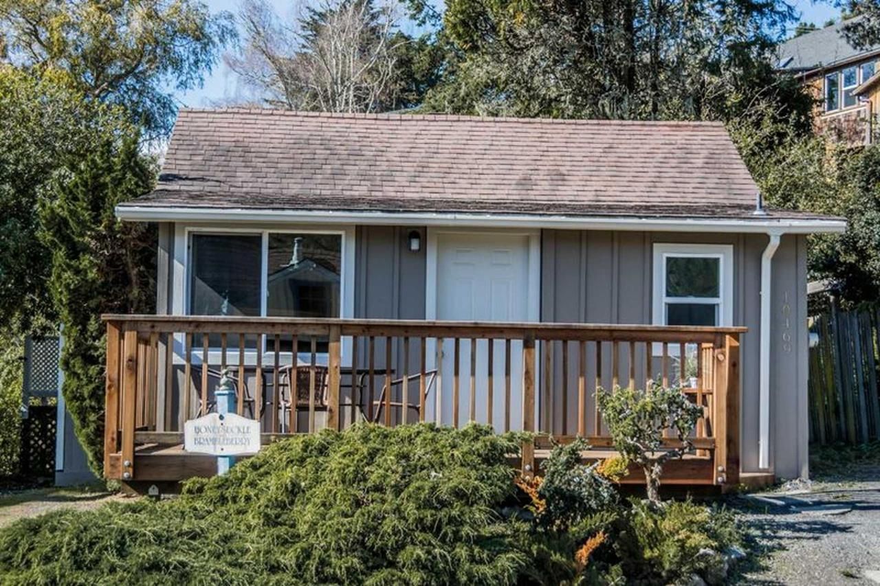 Small cabin with a wooden deck, light brown siding, and a brown roof.
