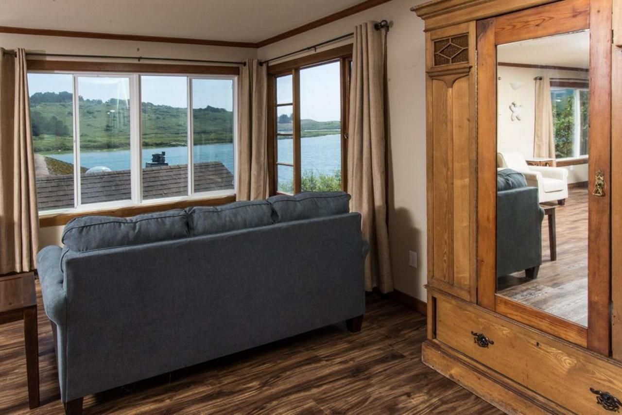 Living room with blue sofa, wooden cabinet, and windows overlooking a lake.