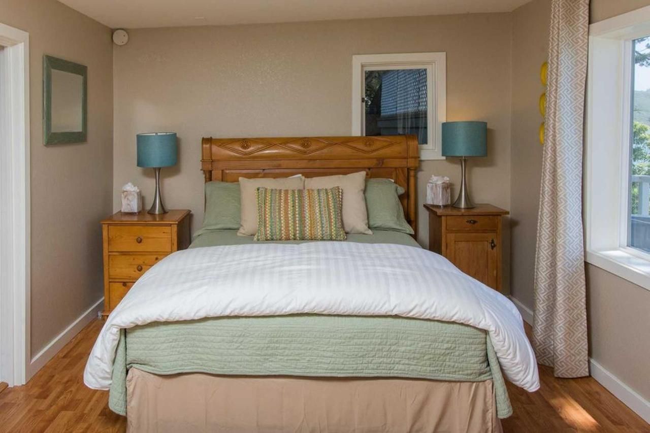Bedroom with wooden furniture, teal lamps, and white and green bedding.