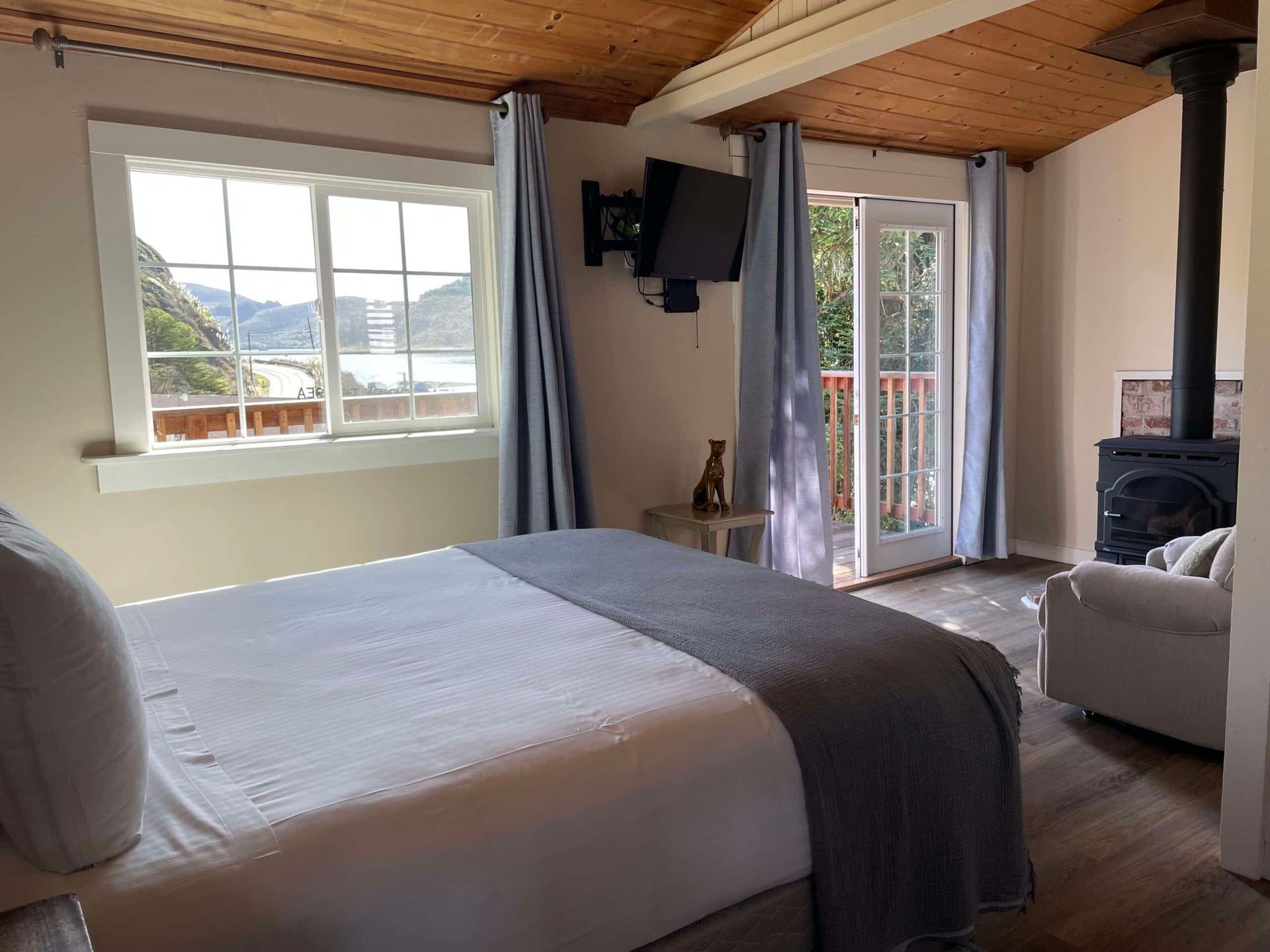 Bedroom with a bed, TV, window overlooking water, and a fireplace.