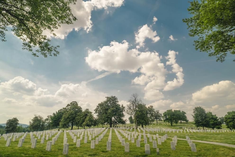 Wide view of a peaceful cemetery with rows of gravestones under a bright sky, representing a funeral home and cremations Lyons, IL.