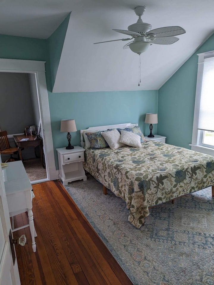 A bedroom with a bed , nightstands , lamps and a ceiling fan.