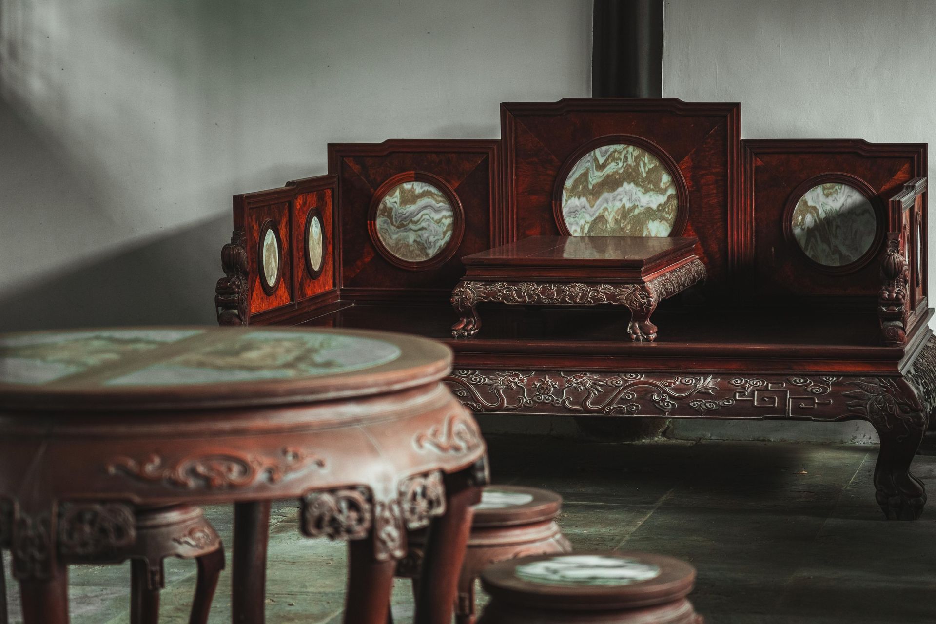 A living room with a wooden couch , table and stools.