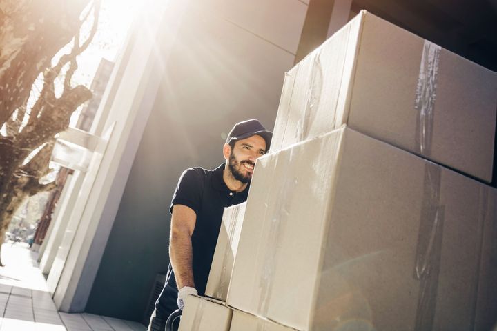 A man is carrying a stack of cardboard boxes.