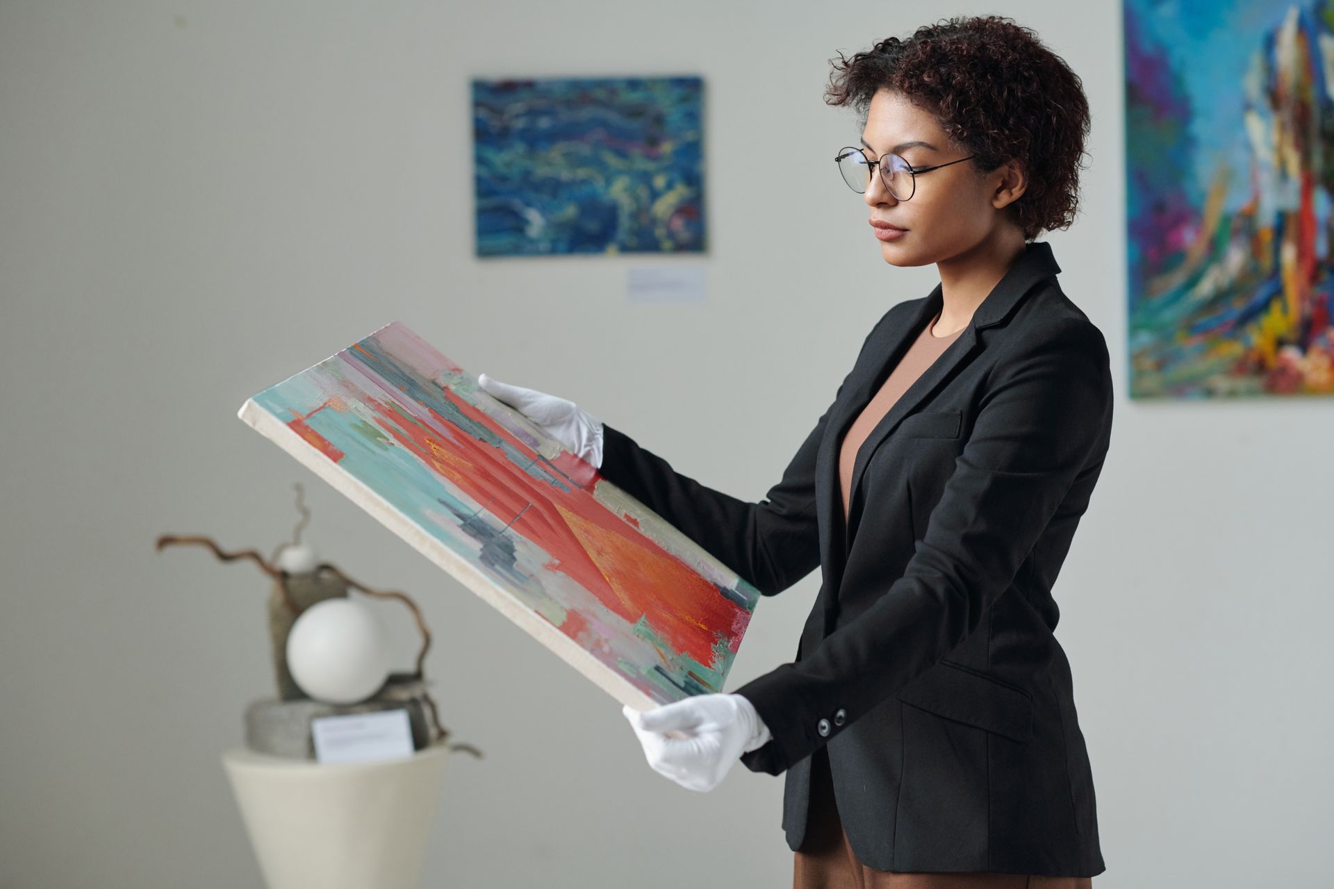 A woman is holding a painting in her hands in a museum.