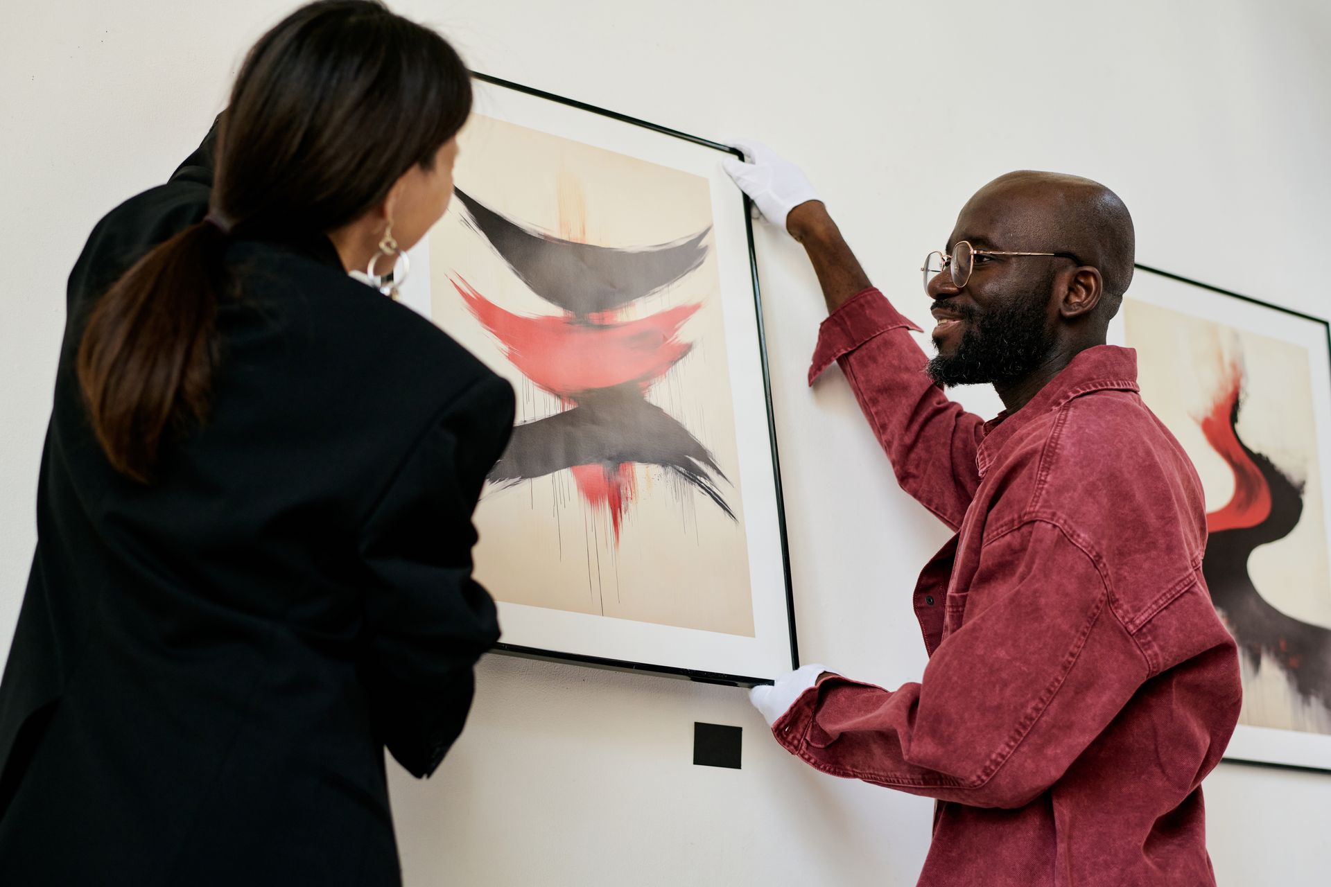 An elderly man is hanging a picture on a wall.