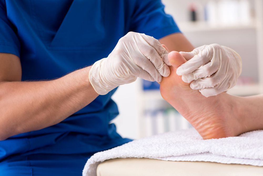 A Doctor is Examining a Patient's Foot in a Hospital — Newcastle Foot & Ankle Clinic Charlestown In Charlestown, NSW