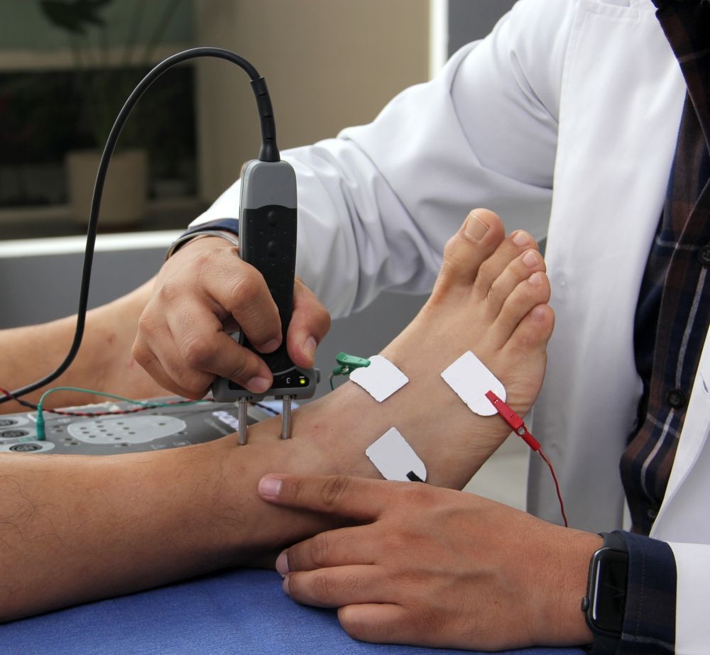 A Doctor is Using a Device on a Patient's Foot — Newcastle Foot & Ankle Clinic Charlestown In Charlestown, NSW