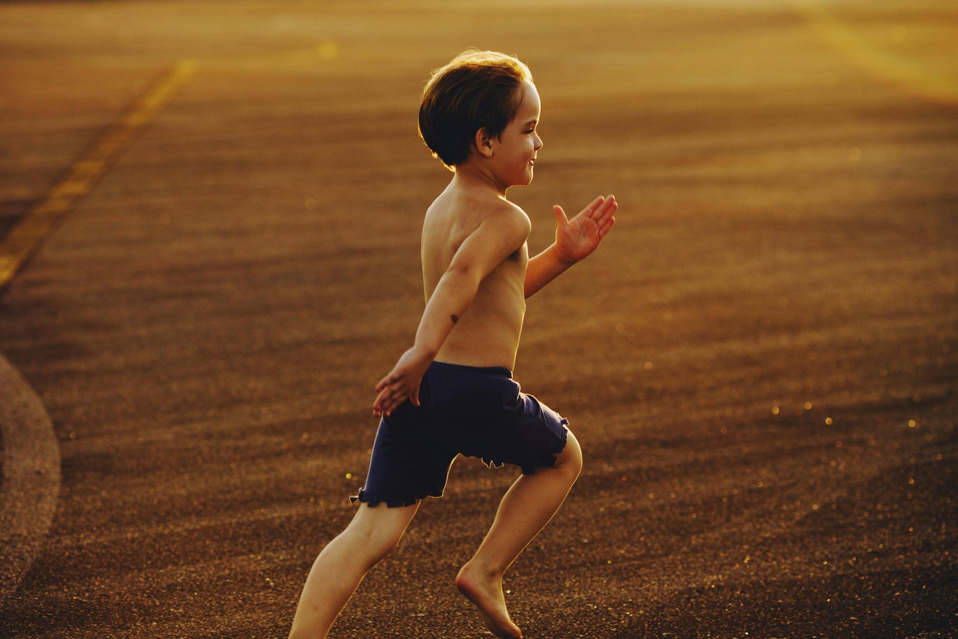 A young boy is running barefoot on a dirt road — Newcastle Foot & Ankle Clinic Charlestown In Charlestown, NSW