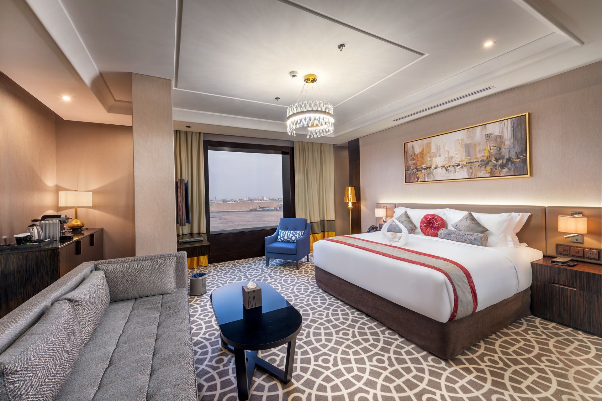 Luxurious hotel room with king bed, sofa, city view, and decorative rug.