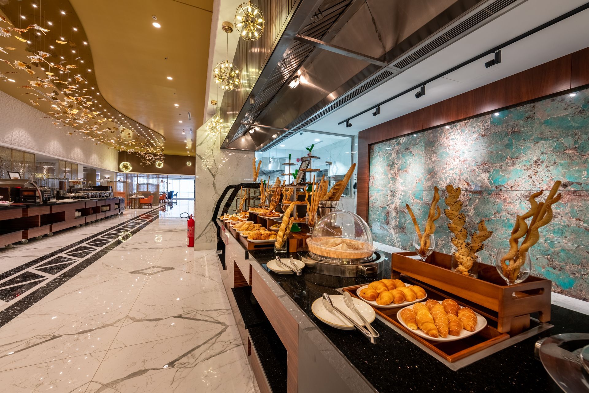 Buffet with bread, pastries, and other food items displayed on a long counter.