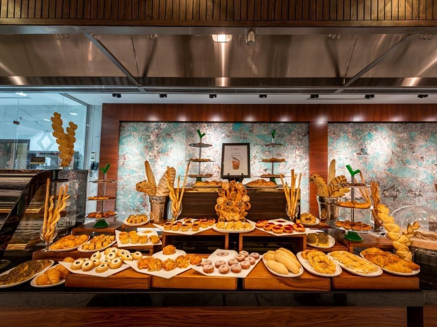 A buffet table laden with various baked goods: breads, pastries, and breadsticks.