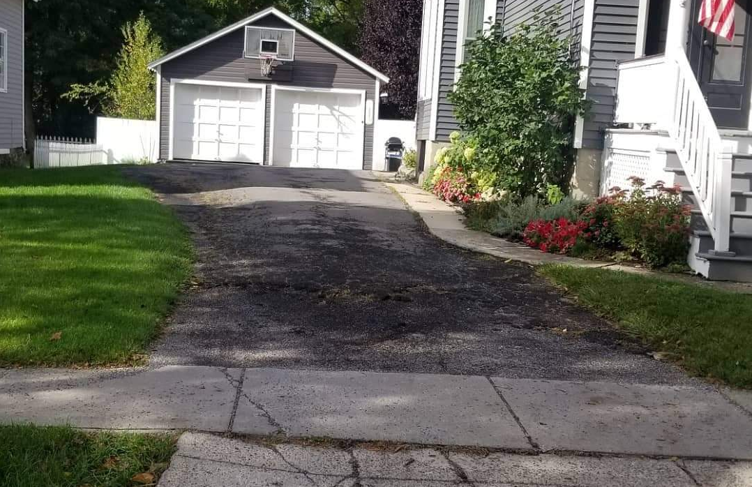 a driveway leading to a garage with a basketball hoop on top of it