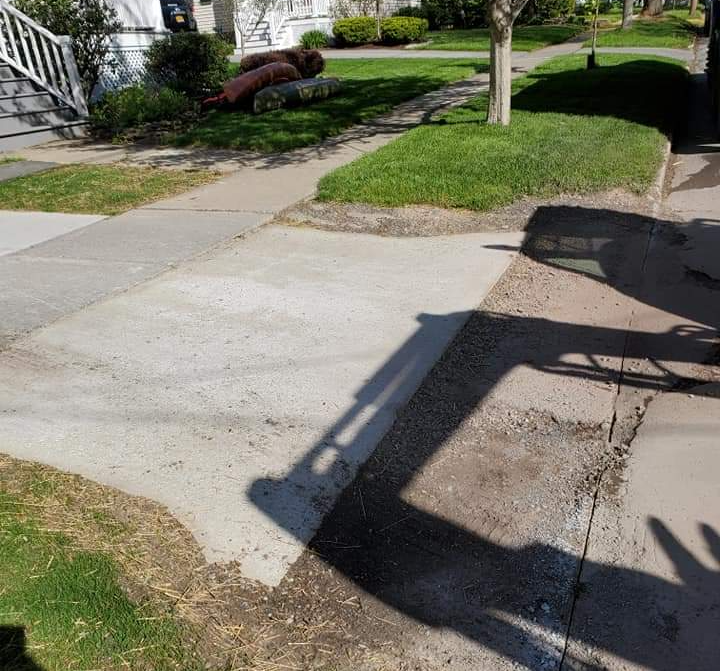 a shadow of a tractor is cast on a concrete sidewalk .