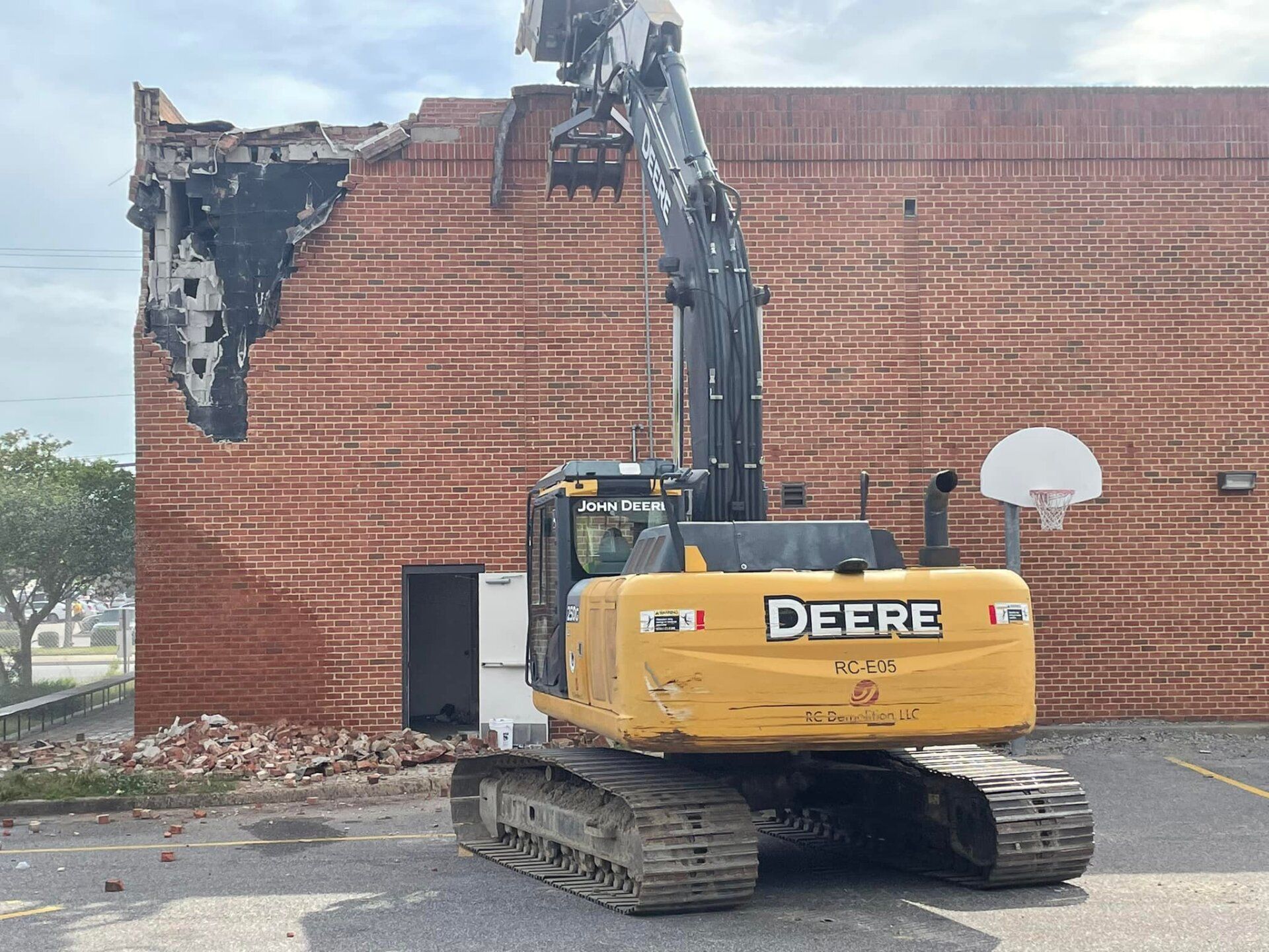a deere excavator is demolishing a brick building