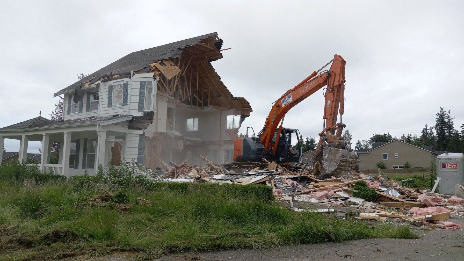 a house is being demolished by a hitachi excavator