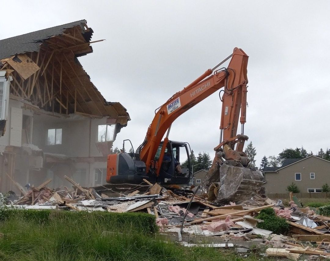 an orange hitachi excavator is demolishing a house