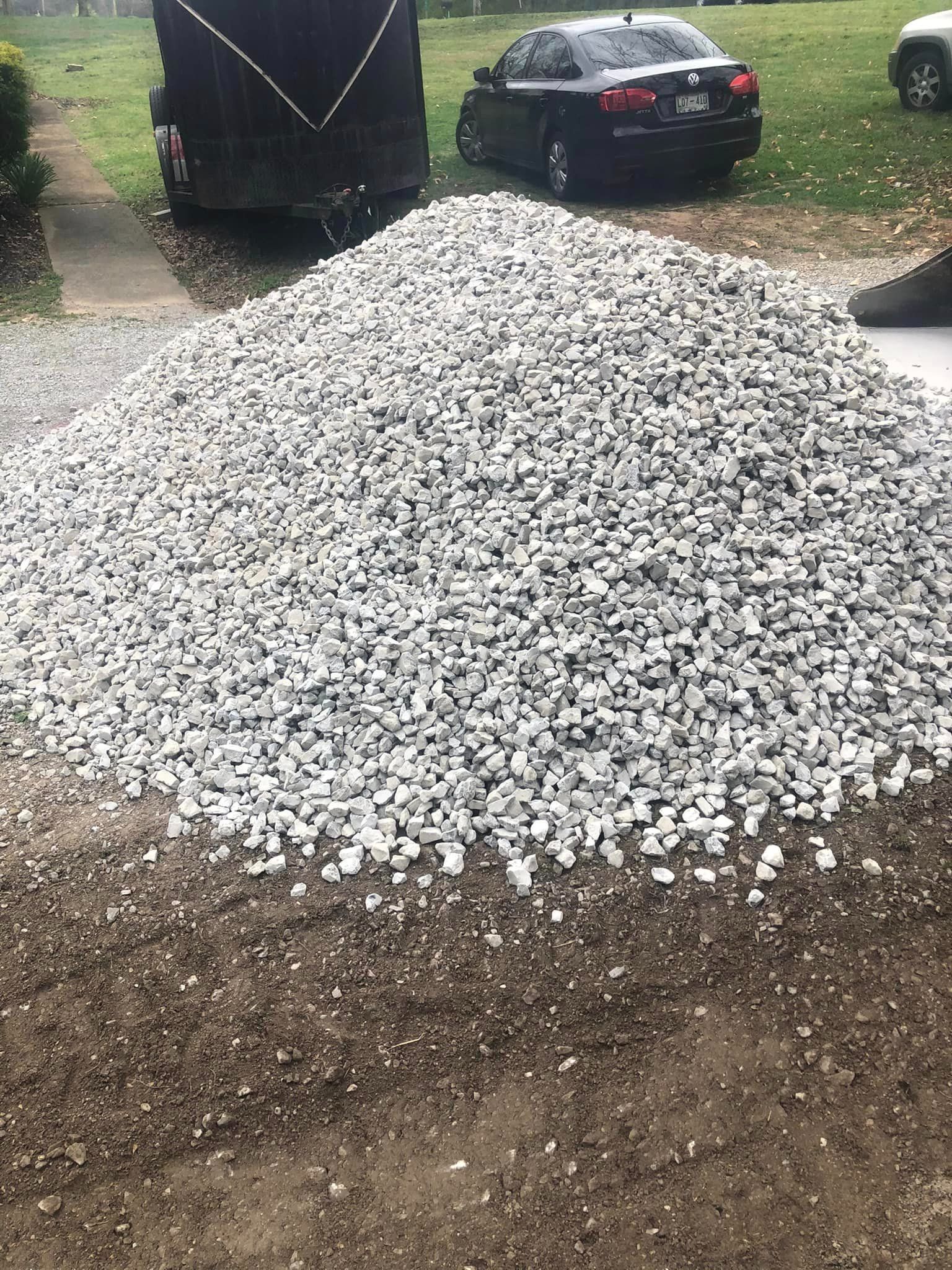 A pile of gravel is sitting on the ground next to a car.