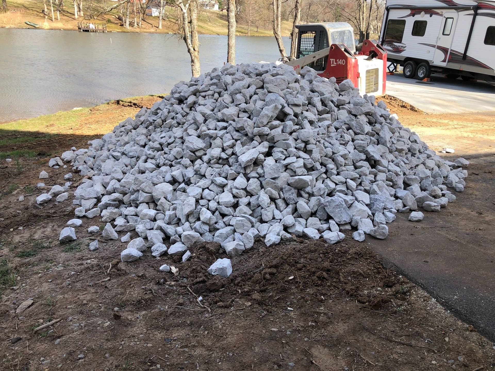 A pile of rocks is sitting on the ground next to a lake.