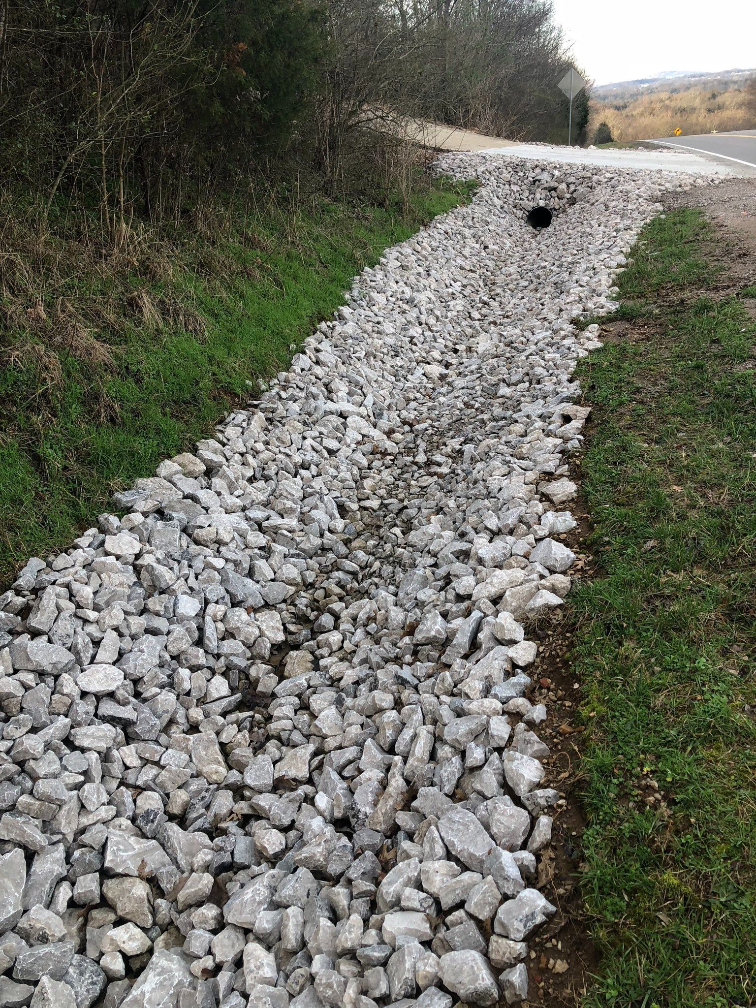 A gravel path going through a grassy area next to a road.