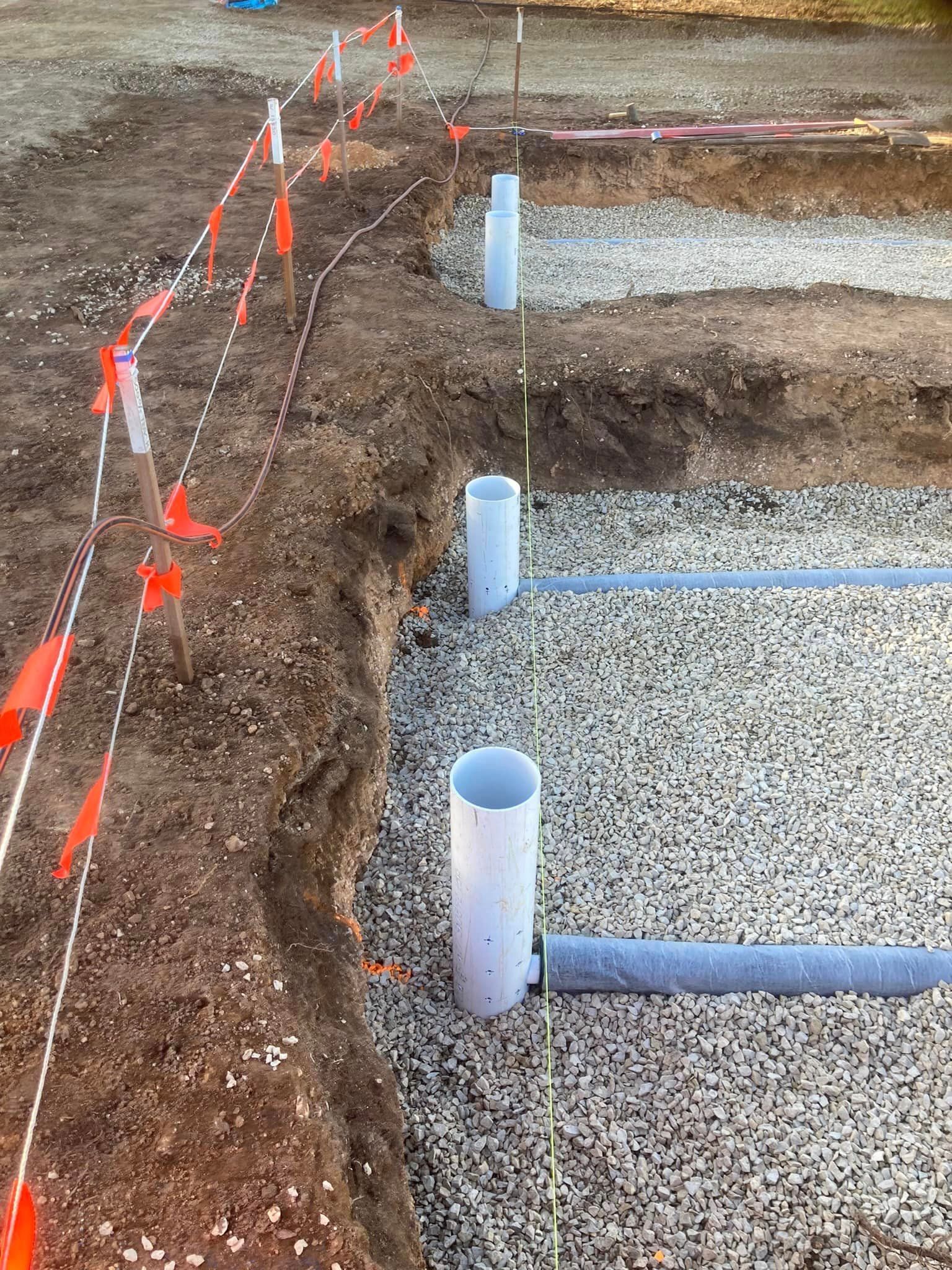 A construction site with a lot of pipes in the dirt.