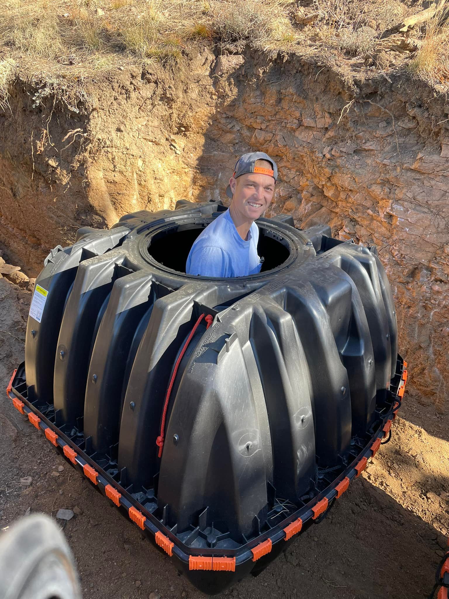 A man is sitting inside of a large black plastic container.