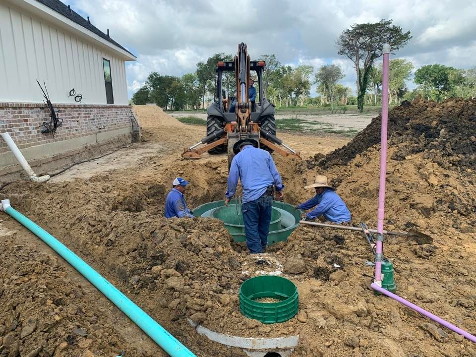 A group of men are working on a septic system in the dirt.