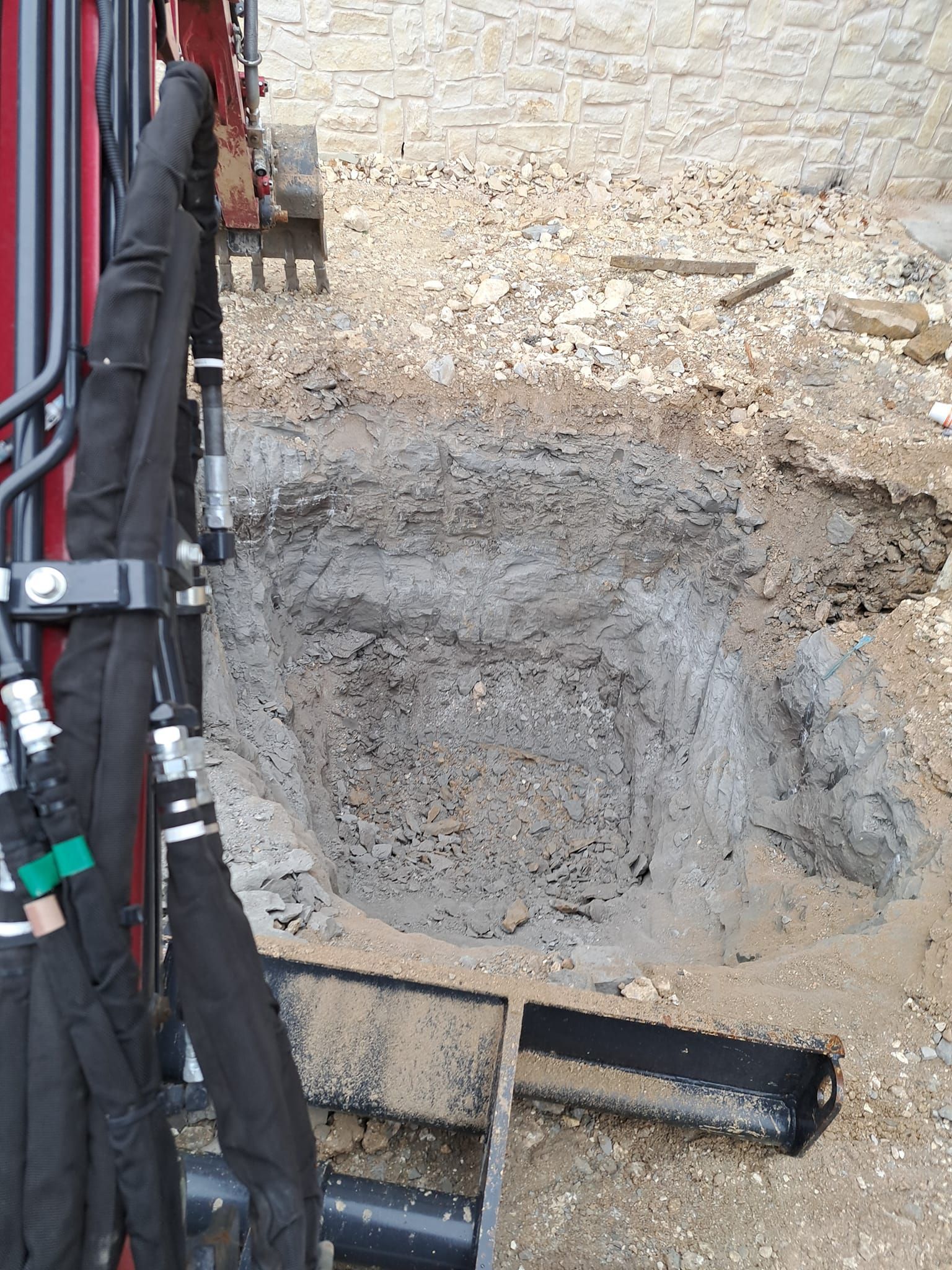 A red and black excavator is digging a hole in the dirt.