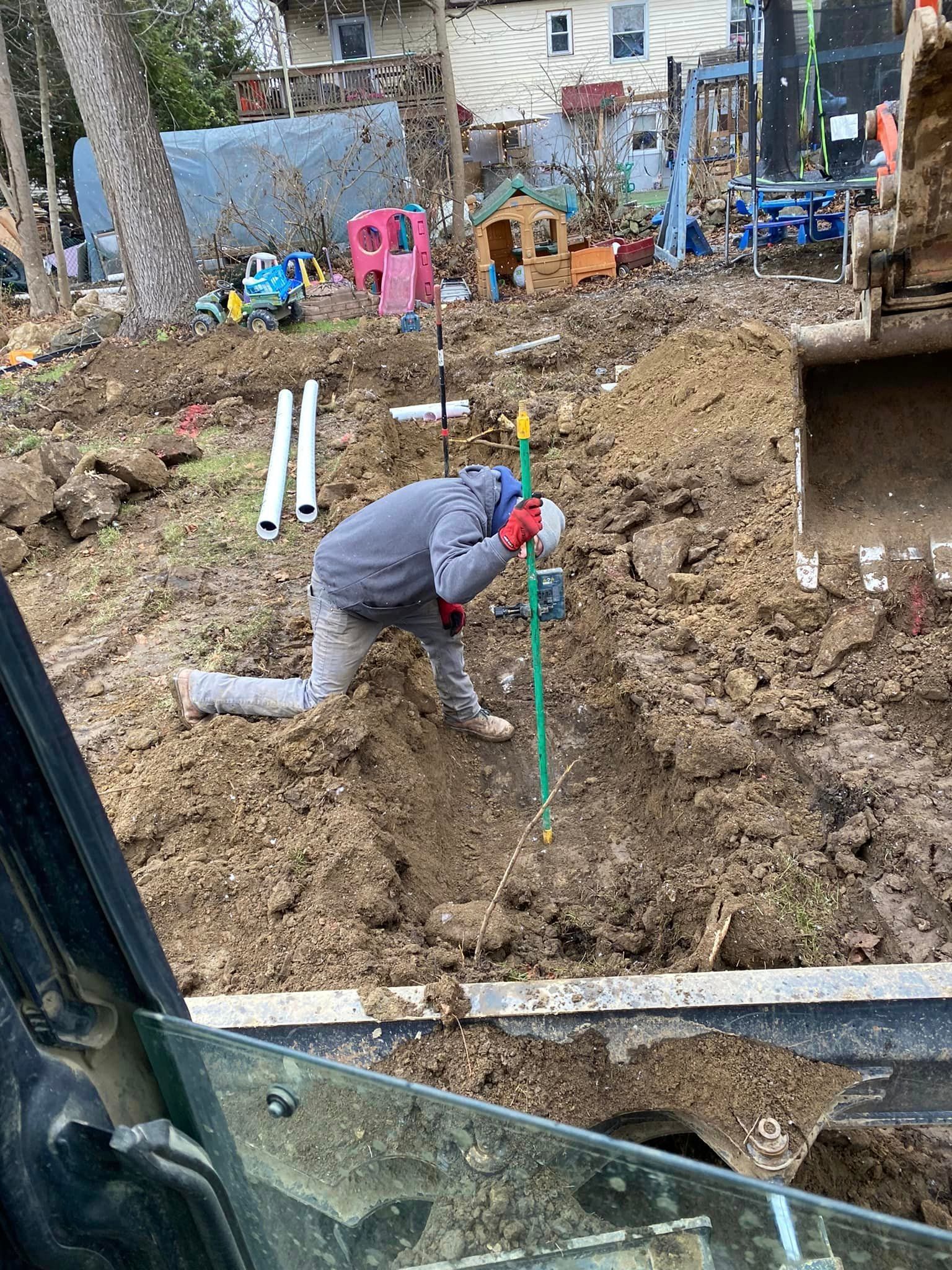 A man is kneeling in the dirt in a construction site.