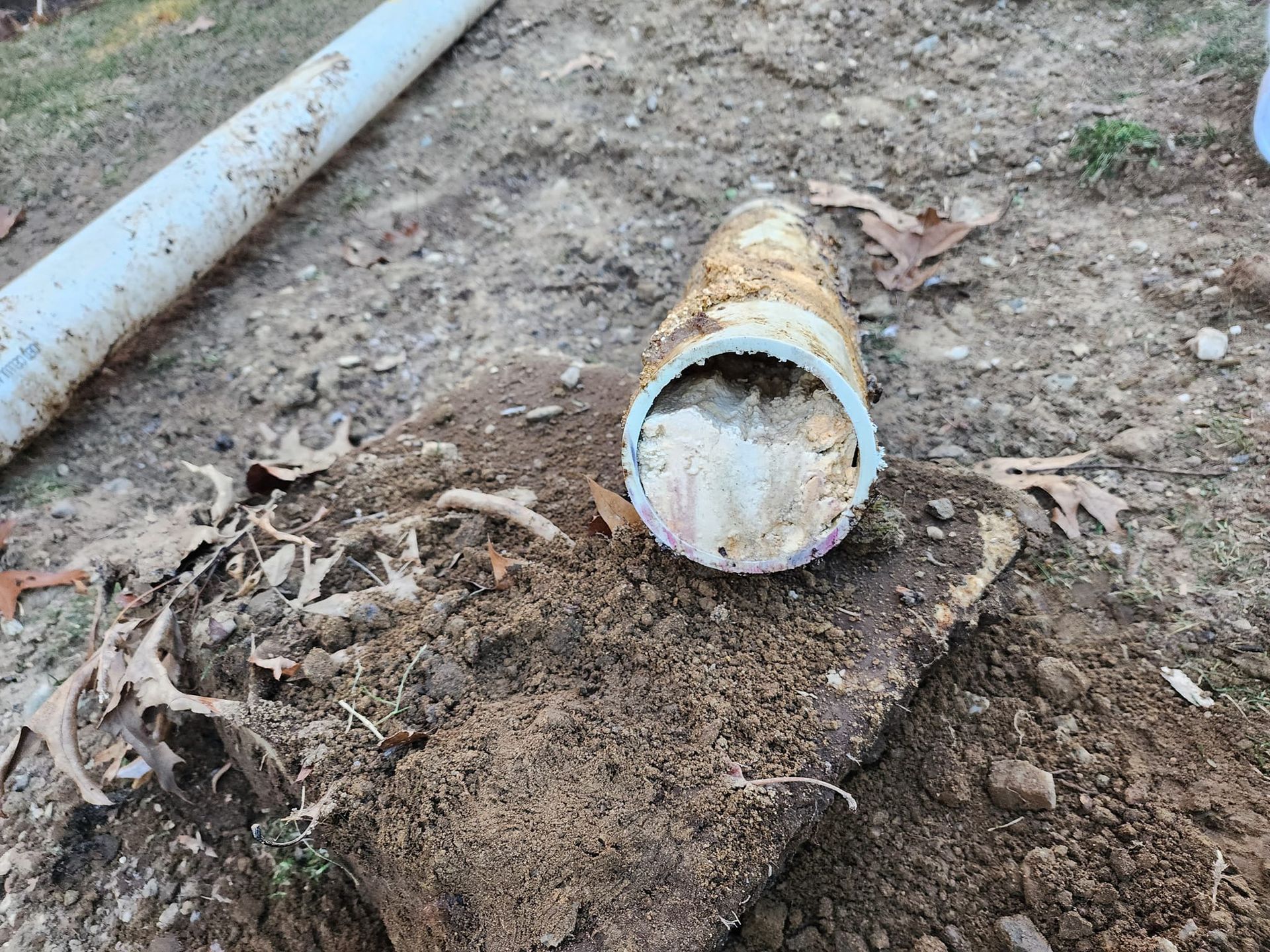 A dirty pipe is sitting on top of a pile of dirt.