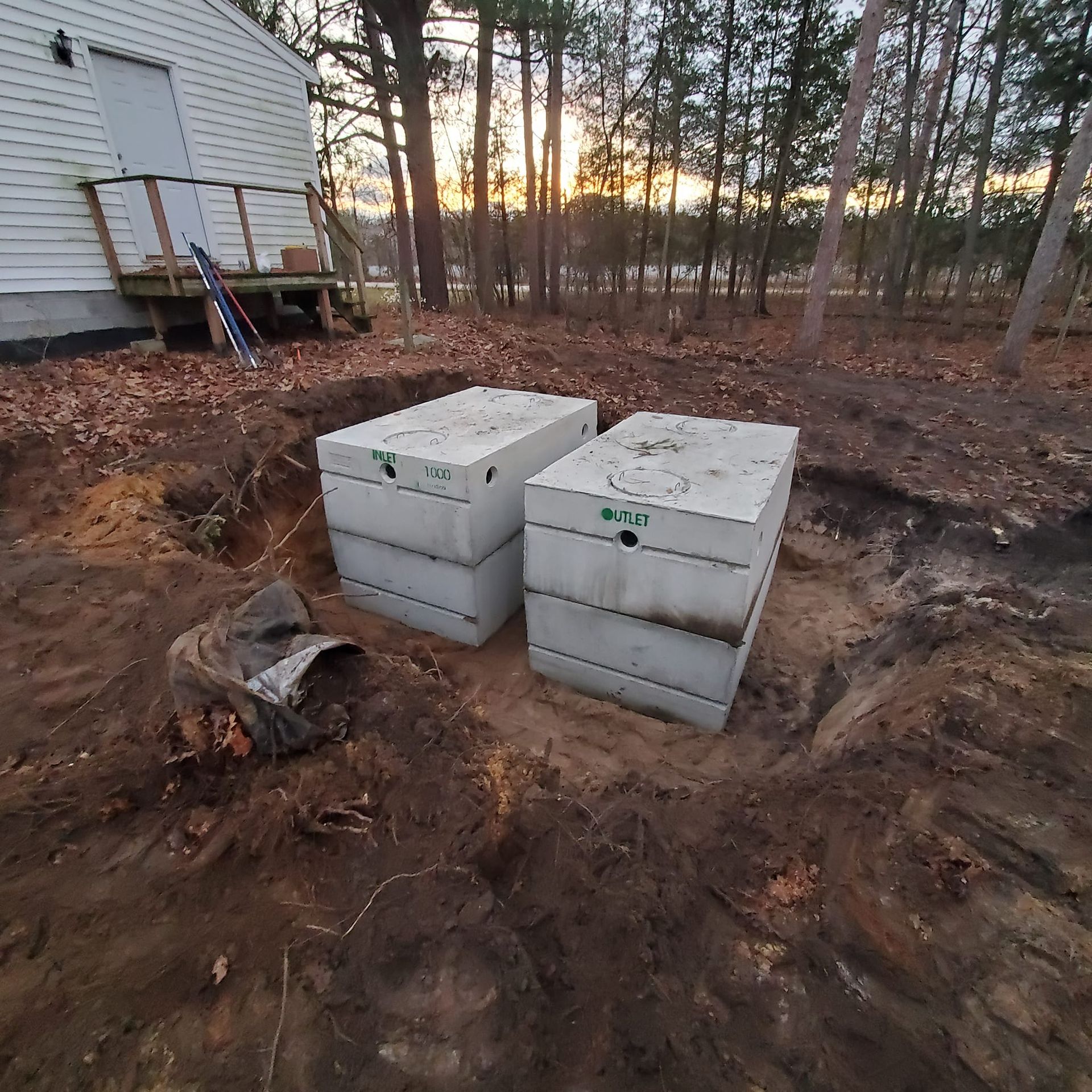 Two septic tanks are sitting in the dirt in front of a house