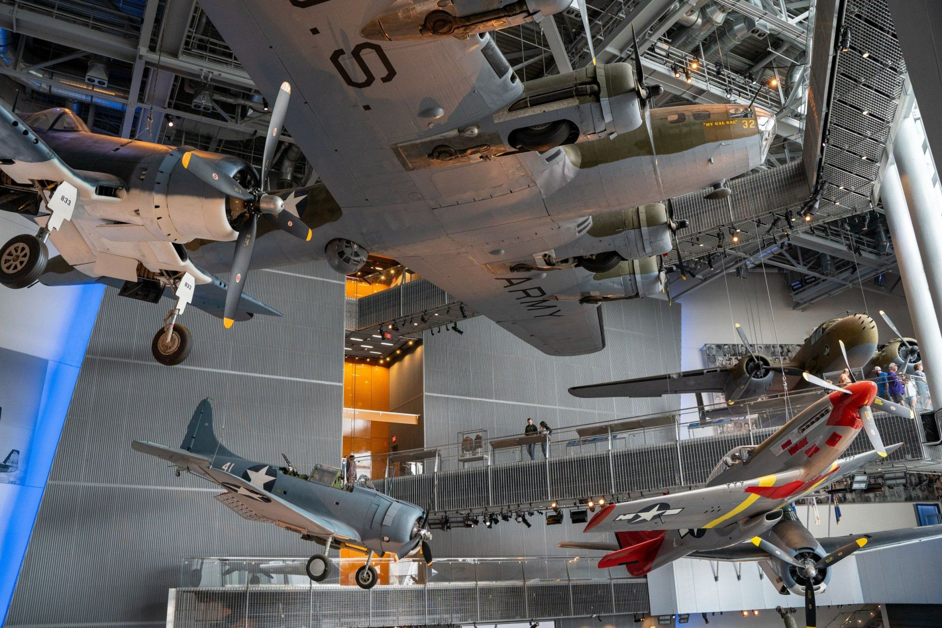 an army plane hangs from the ceiling of a museum