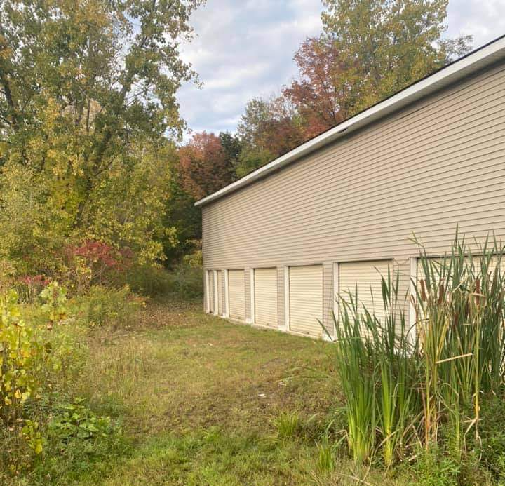 a large building with a lot of garage doors is surrounded by tall grass and trees .