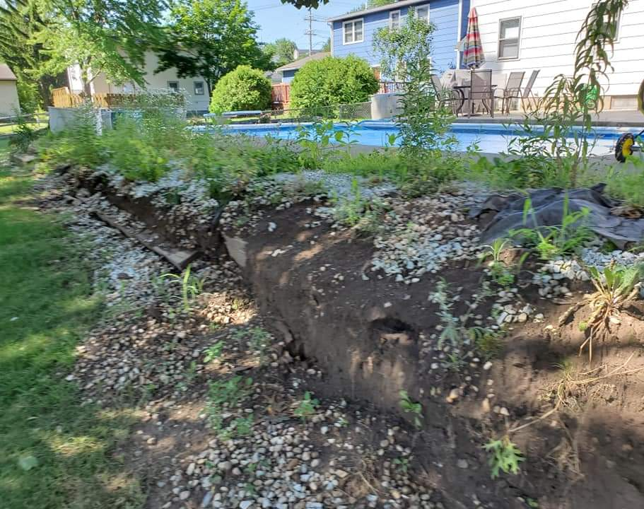 a large pile of dirt is in front of a swimming pool .