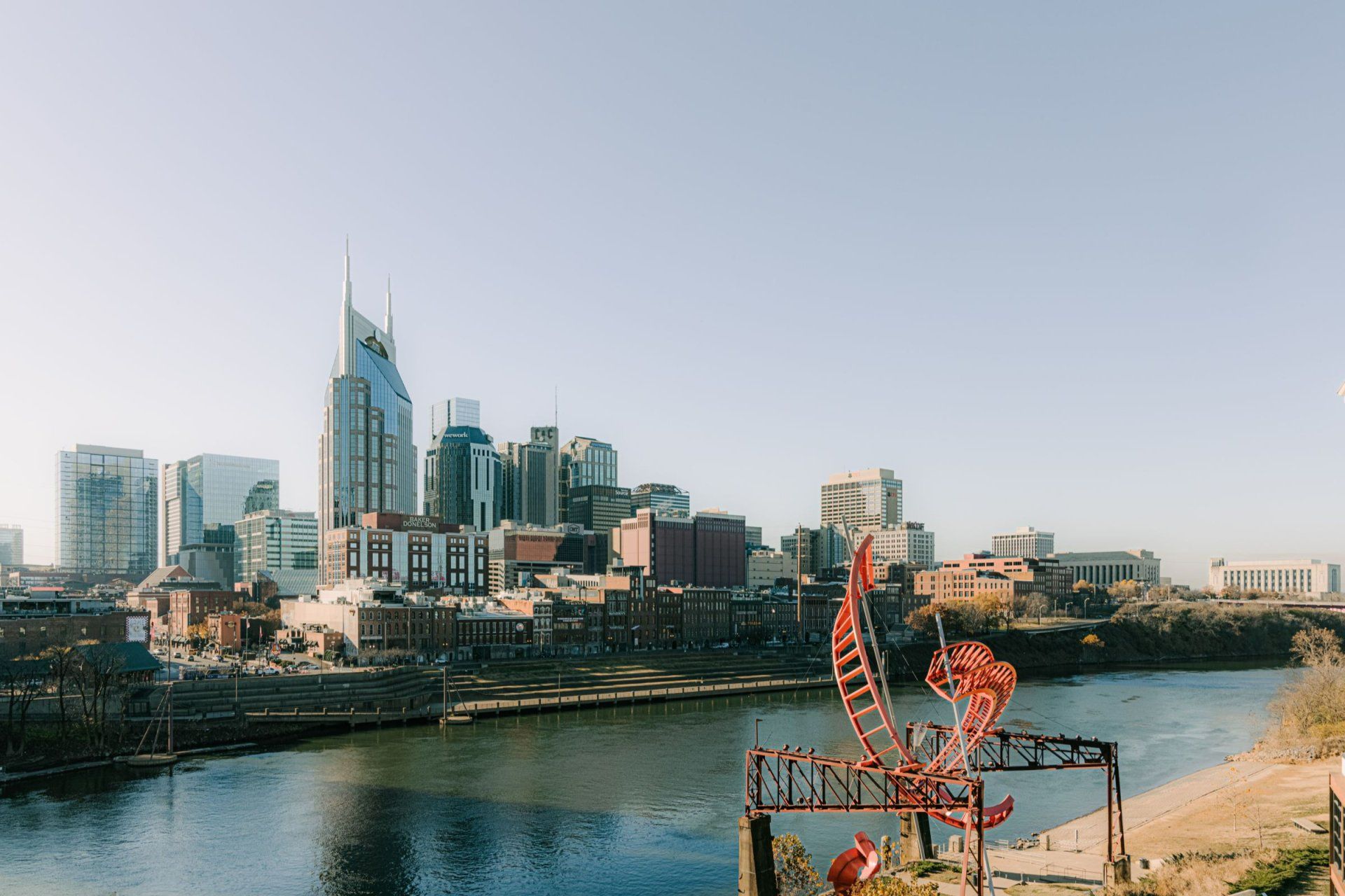 a city skyline with a red sculpture in the foreground