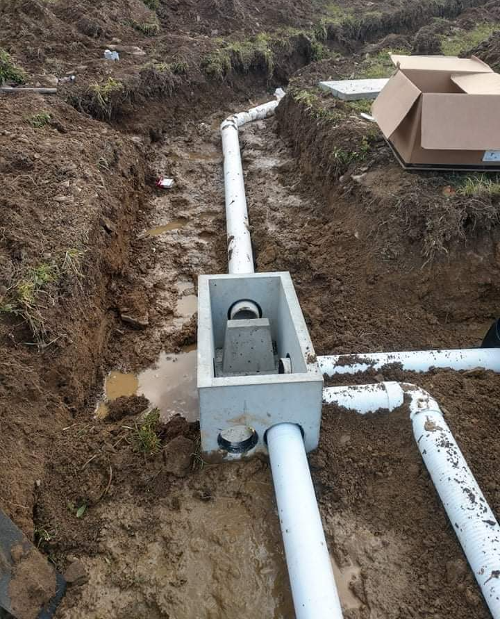 white pipes are connected to a concrete box in the dirt