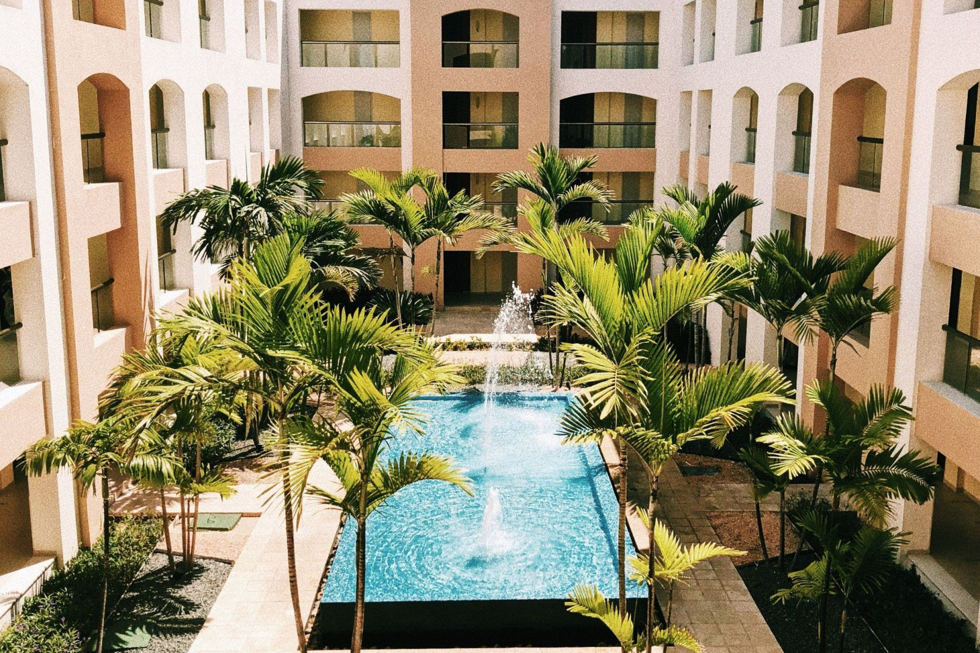 a swimming pool in the middle of a building surrounded by palm trees