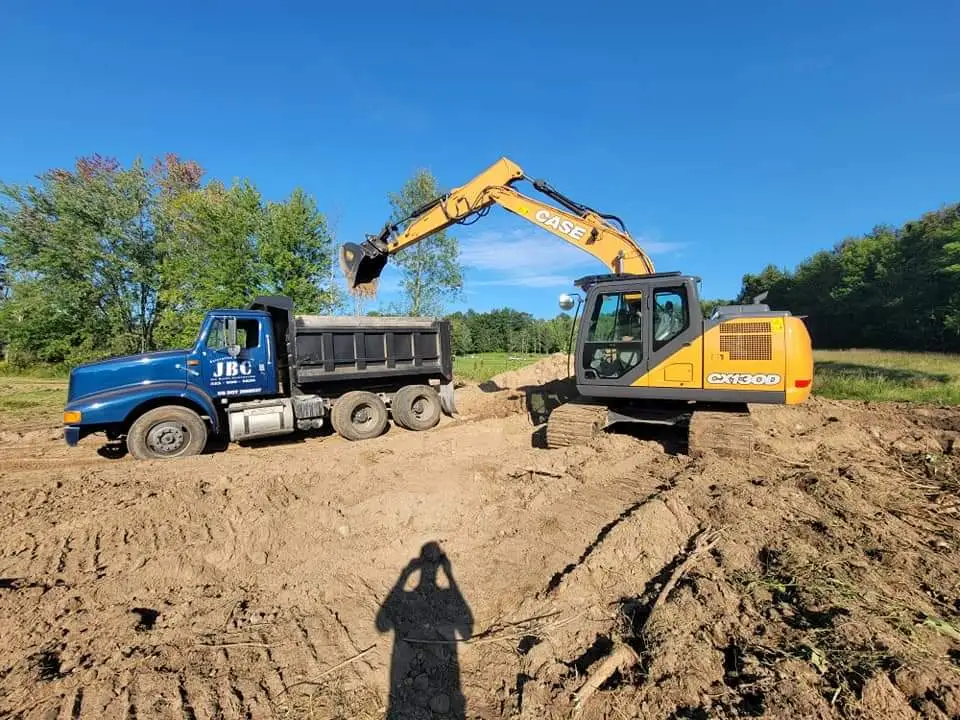 a case excavator is loading dirt into a dump truck