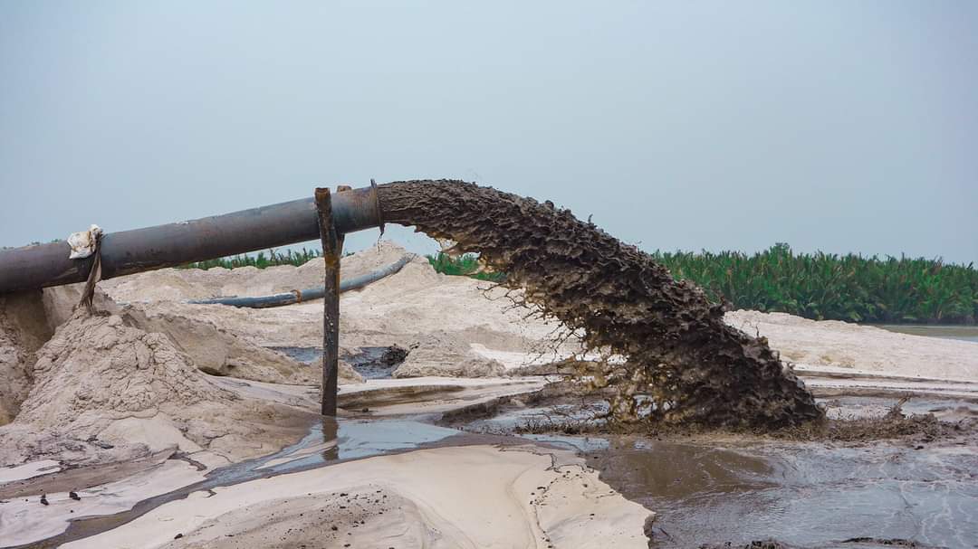 a large pipe is pouring dirt into a body of water
