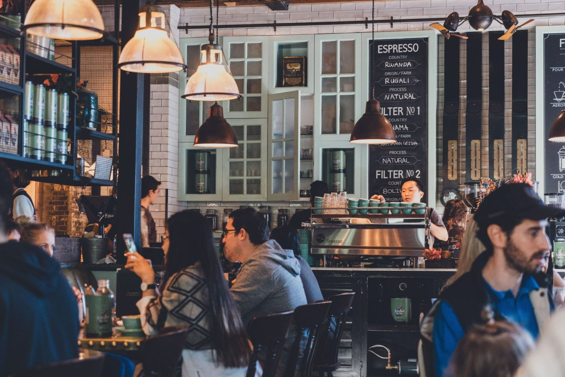 people sitting at tables in front of a sign that says espresso